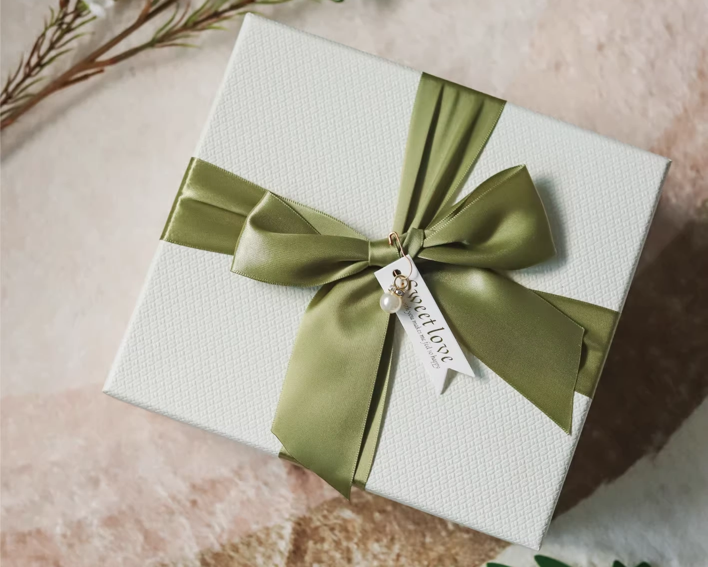A high-quality white rigid box, open to reveal a velvet interior, tied with a thick white satin ribbon bow.